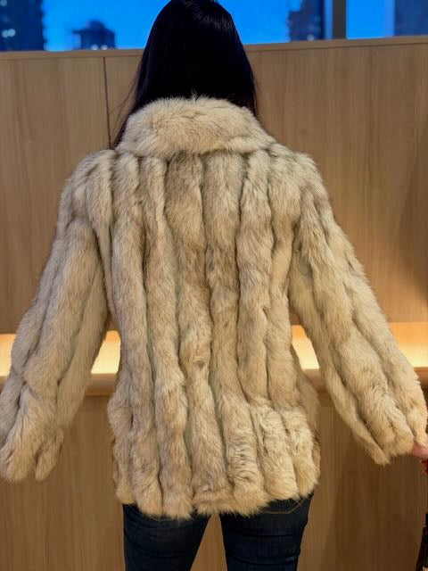 Person wearing a beige fur coat with a blurred background